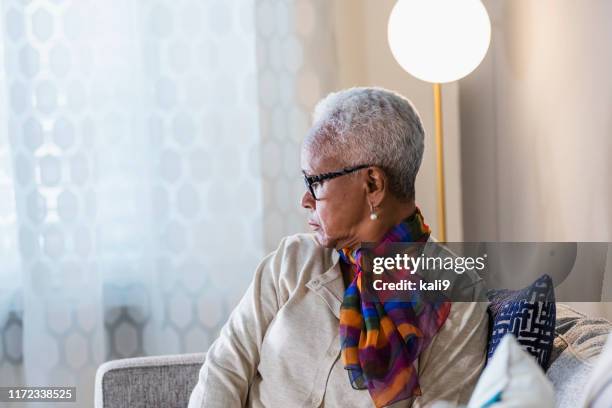 senior african-american woman looking through window - woman looking over shoulder serious stock pictures, royalty-free photos & images