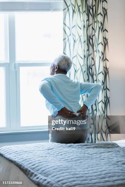 senior african-american woman with sore back - back pain bed stock pictures, royalty-free photos & images