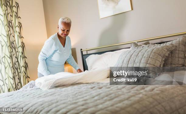 senior african-american woman making the bed - made bed stock pictures, royalty-free photos & images