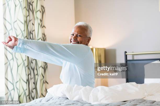 senior african-american woman aufwachen - morning bed stretch stock-fotos und bilder