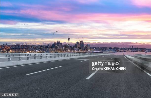 empty tarmac road against sunset urban auckland city - auckland stock pictures, royalty-free photos & images