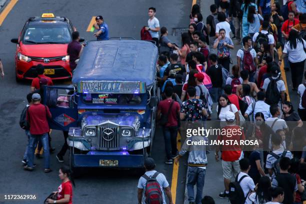 Commuters jostle with each other to ride on a passenger jeepney as transport strike starts in Manila on September 30 as the government move to phase...
