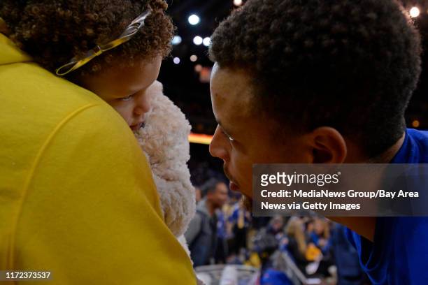 Golden State Warriors' Stephen Curry speaks to his daughter Riley Curry before playing the Milwaukee Bucks at Oracle Arena in Oakland, Calif., on...