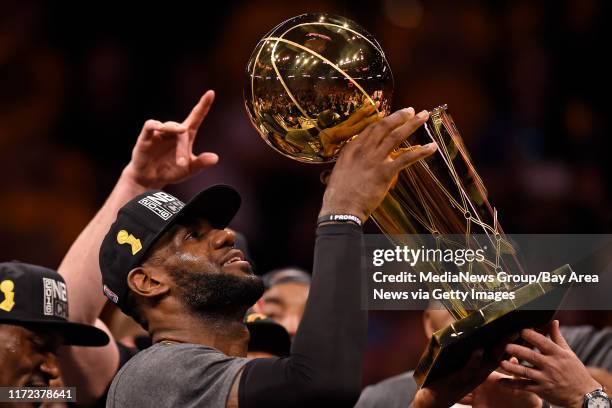 Cleveland Cavaliers' LeBron James holds up the Larry O'Brien trophy after defeating the Golden State Warriors in Game 7 of the NBA Finals at Oracle...