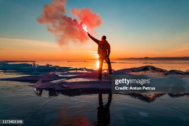 man with hand flare at sunset on ice. baikal in winter - pioneer photographer of motion stock pictures, royalty-free photos & images