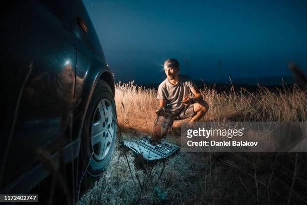 car repair. lucky me. changing car tire in the middle of nowhere at dusk. diy - roadside challenge stock pictures, royalty-free photos & images