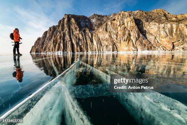 photographer on the background of a rocky cape on lake baikal in winter - baikal stock-fotos und bilder
