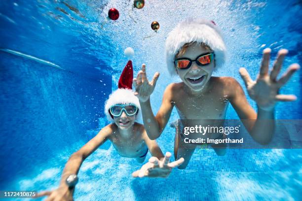 kids playing with baubles in pool on summer christmas - swimming goggles stock pictures, royalty-free photos & images