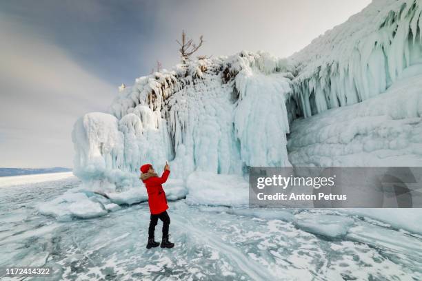 girl takes pictures of the icy shore of the island on lake baikal - arctic explorer stock pictures, royalty-free photos & images