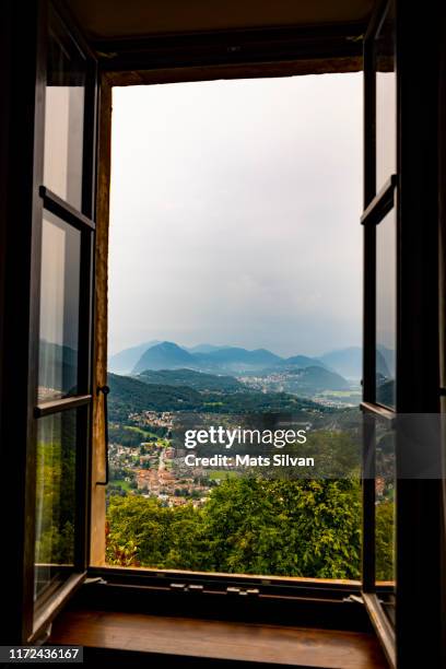 window view over landscape with mountain range and village - schweiz stadt landschaft stock-fotos und bilder