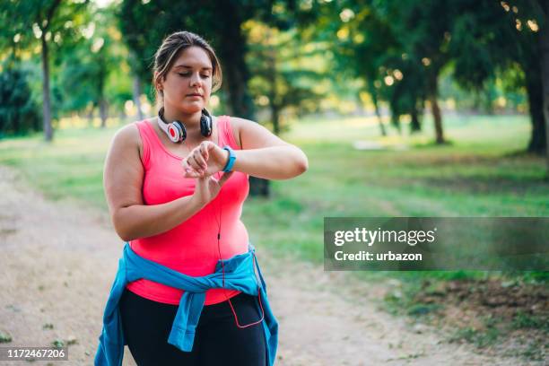 female overweight runner checking smart watch - taking pulse stock pictures, royalty-free photos & images