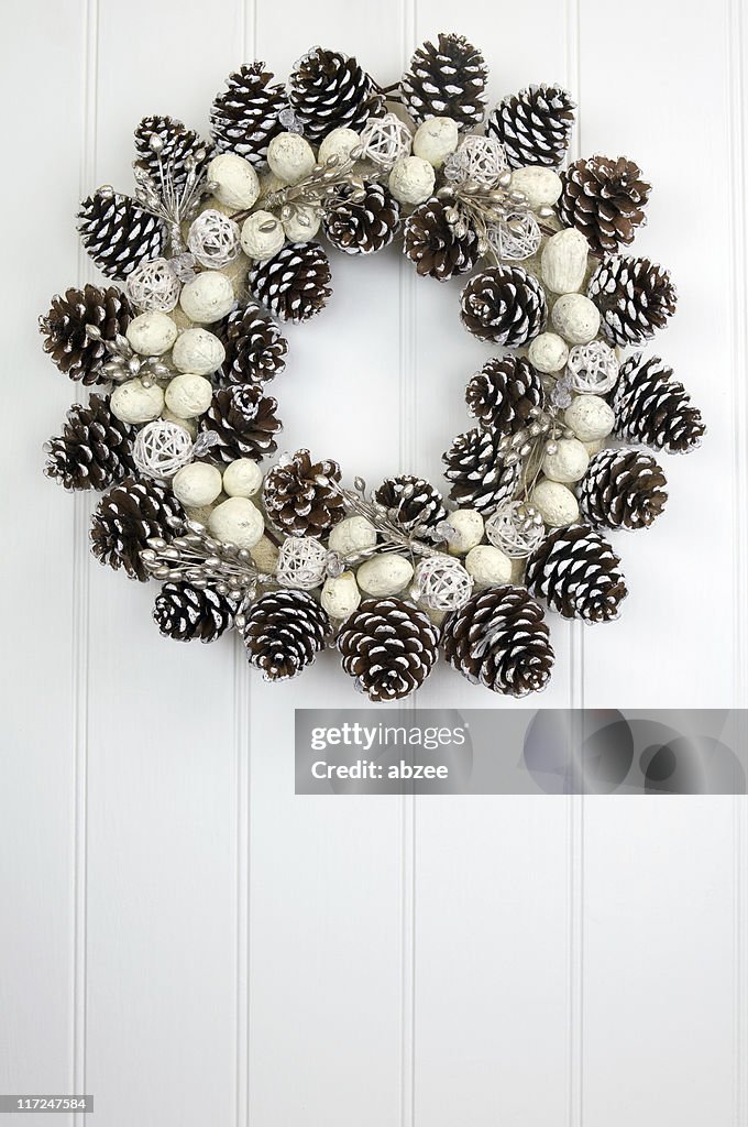 Pine cone wreath on white paneled wall