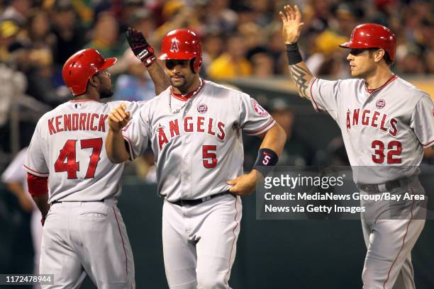 Los Angeles Angels' Howie Kendrick welcomes home Albert Pujols and Josh Hamilton after scoring on Mark Trumbo two-run single against the Oakland...