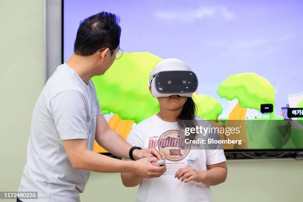 Teacher helps a student using a virtual reality headset in a class at Daeseong-dong elementary school during a media tour of Daeseong-dong village in...