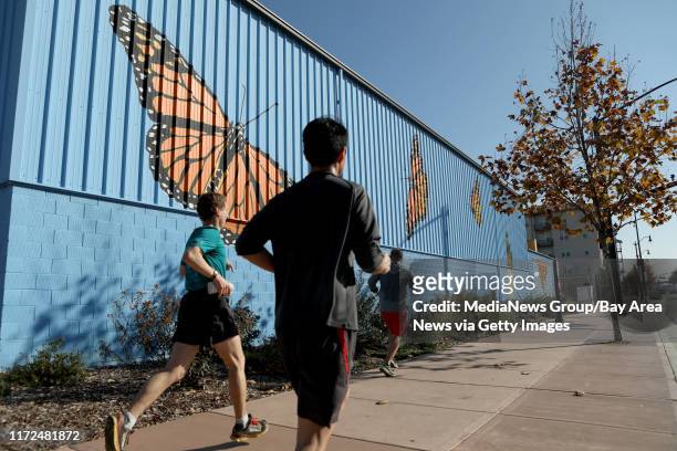 Joggers run past a butterfly mural along San Leandro Boulevard in San Leandro, Calif., on Thursday, Dec. 14, 2017.