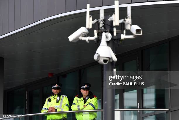 British Police officers stand on duty near CCTV cameras on the second day of the annual Conservative Party conference at the Manchester Central...