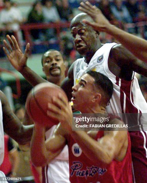 Carlos Arroyo of Puerto Rico tries to shoot the ball despite his huge defender, Venezuela's Carl Herrera, during the second round of the Pre-World...