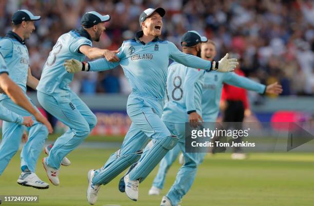 Jos Buttler celebrates with other England players after he runs out Martin Guptill off the final ball of the superover to give England victory during...