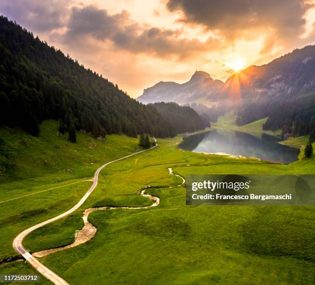 white road and winding river and samtisersee at sunrise, canton appenzell, switzerland. - appenzell stock-fotos und bilder