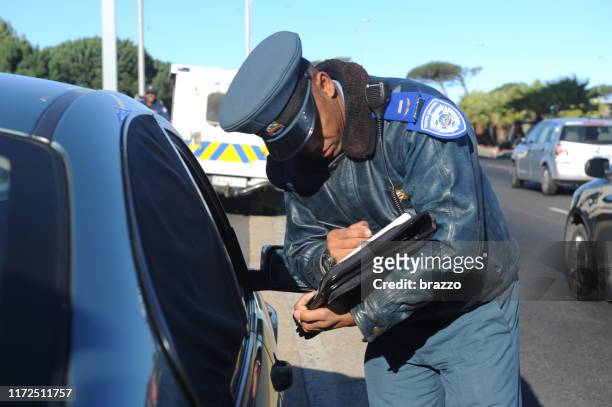 o polícia dá a um motorista um bilhete da violação de tráfego - traffic police officer - fotografias e filmes do acervo