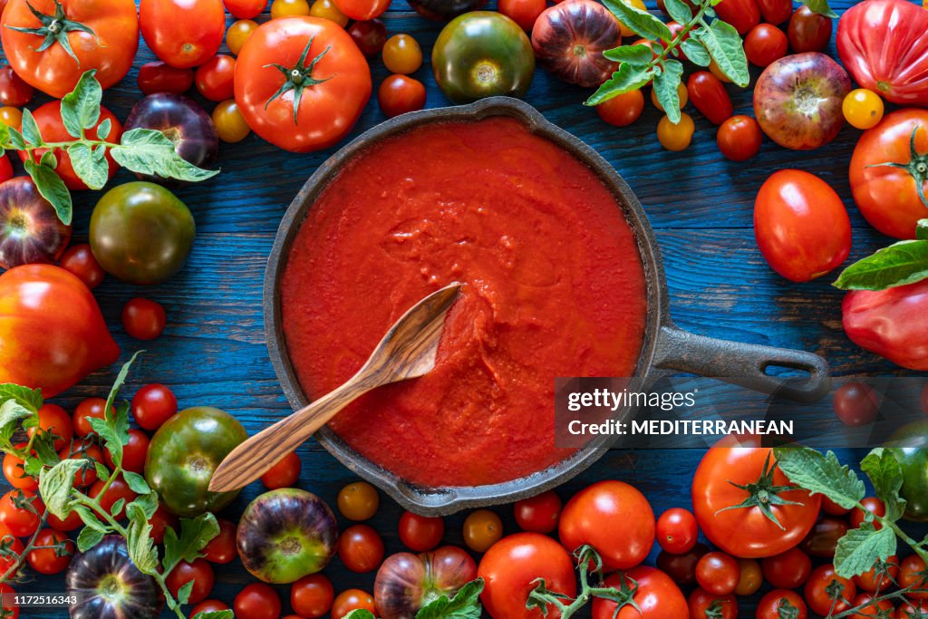 Salsa de tomate frito con tomates sobre madera