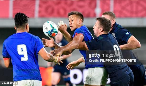 Samoa's full back Tim Nanai-Williams passes the ball to Samoa's scrum-half Melani Matavao as he is tackled by Scotland's scrum-half Greig Laidlaw...