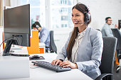 Female professional call center telesales agent wear wireless headset using computer in customer care support service office with team.