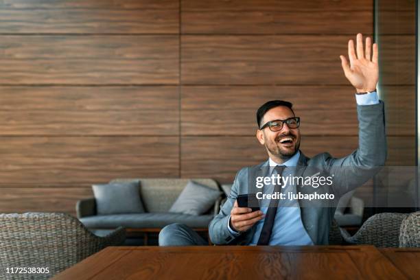 smiling businessman greeting friend while sitting - hand waving stock pictures, royalty-free photos & images