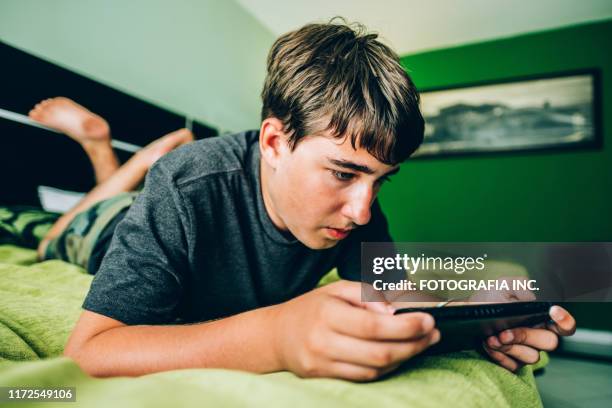 teenage boy playing video games in hotel room - teen boy barefoot stock pictures, royalty-free photos & images