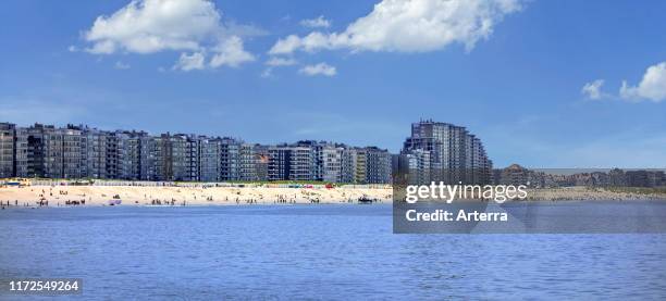 Tourists on the beach and flats and apartments at Nieuport / Nieuwpoort, seaside resort along the North Sea coast, West Flanders, Belgium.