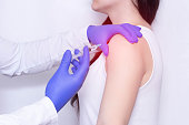Doctor makes an injection of blockade of chondroprotector and anti-inflammatory drug in the girl's sore shoulder, white background, close-up, ozone therapy
