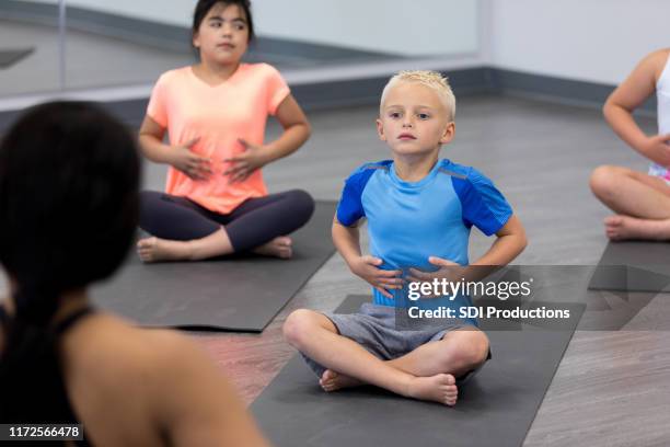 los niños pequeños aprenden a respirar adecuadamente en la clase de yoga - respirar fotografías e imágenes de stock