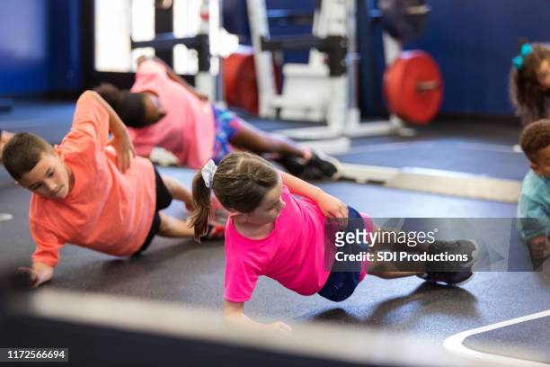 groep kinderen die kant planken uitvoeren tijdens fitnesslessen - boy workout in gym stockfoto's en -beelden