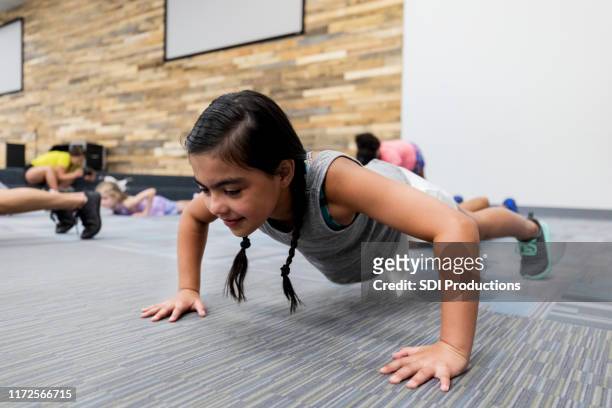 kleines mädchen tun pushups in fitness-klasse - kids fitness stock-fotos und bilder