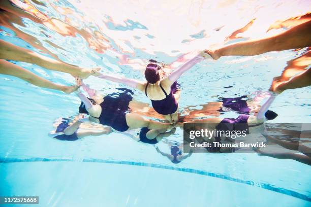 underwater view of senior female synchronized swimmers in formation during routine - synchronized swimming stock pictures, royalty-free photos & images