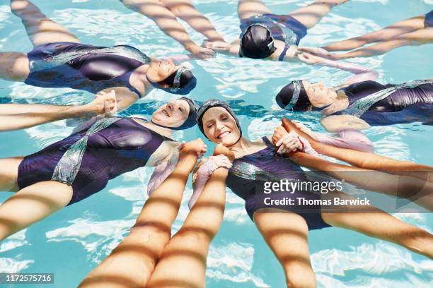 elevated view of senior female synchronized swim team in formation during routine - synchronised swimming stock pictures, royalty-free photos & images