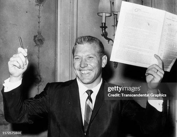 Portrait of American baseball player Mickey Mantle , of the New York Yankees, as he poses with his new annual team contract, New York, New York, 1961.