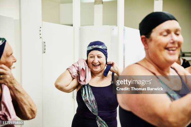 Smiling and laughing senior female synchronized swimmers preparing for show in locker room