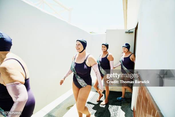 smiling senior female synchronized swim team walking out of locker room before show - synchronized swimming stock-fotos und bilder