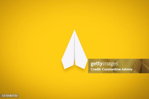 a single paper airplane on yellow background - origami background stockfoto's en -beelden