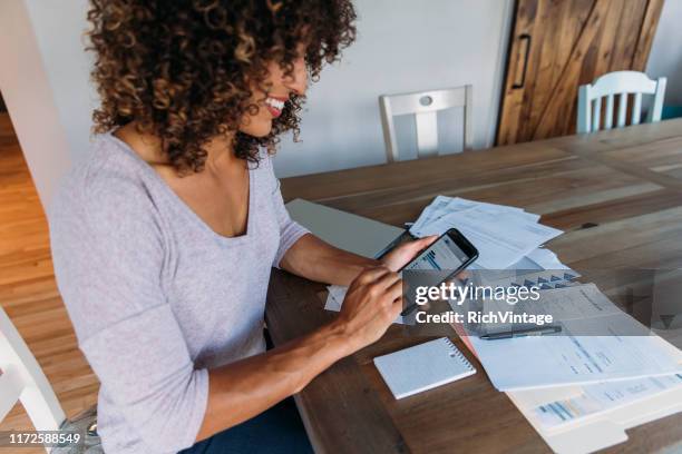 vrouw doet financiën thuis op slimme telefoon - applicatie stockfoto's en -beelden