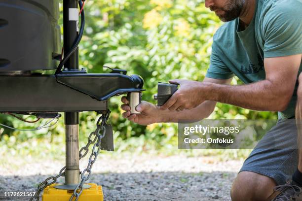 man instalación de camper trailer candado durante camping en verano - remolcar fotografías e imágenes de stock