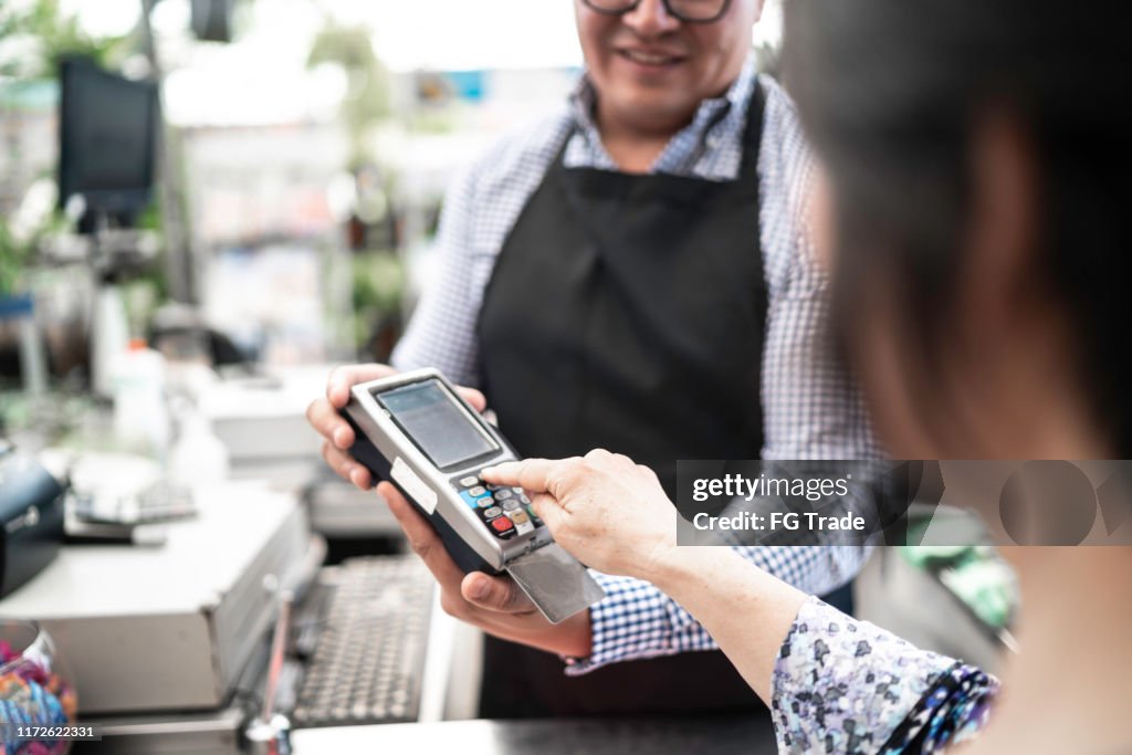 Customer putting the password at credit card payment on checkout counter at small business