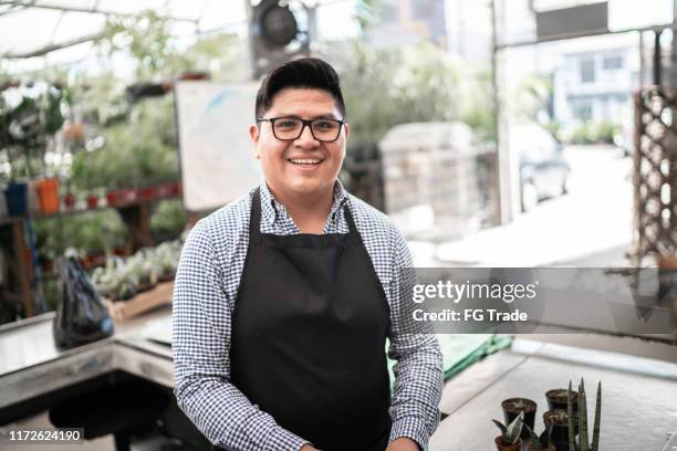 retrato de hombre confiado apoyado en el mostrador de pago en la floristería - mid adult men fotografías e imágenes de stock