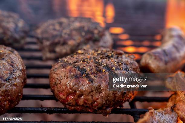 cheeseburgers en brats op een vurige houtskool grill met vlammen - burger grill stockfoto's en -beelden