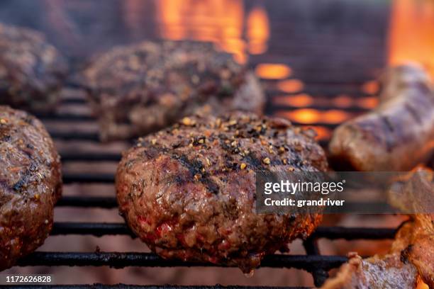 cheeseburgers and brats on a fiery charcoal grill with flames - sausage patty stock pictures, royalty-free photos & images