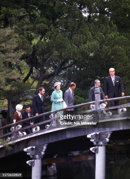 Queen Elizabeth and Prince Philip and their entourage stop on stone bridge in the grounds of the Ise Grand Shrine, a Shinto temple, during her one...