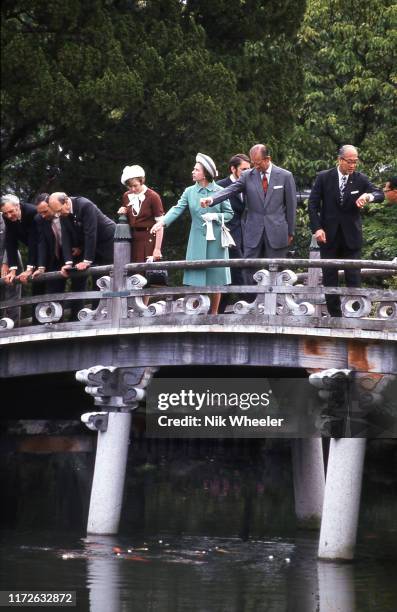 Queen Elizabeth II and Prince Philip and their entourage stop on stone bridge in the grounds of the Ise Grand Shrine, a Shinto temple, during her one...