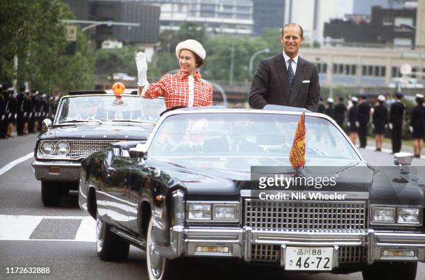 Queen Elizabeth and Prince Philip drive through Tokyo streets in open limousine during Royal Tour of Japan in May 1975