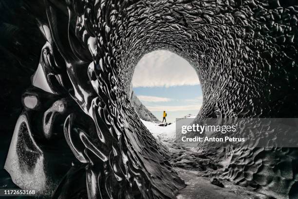 man exploring an amazing glacial cave in iceland - explorer photos et images de collection